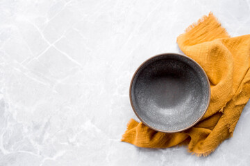 Banner. An empty ceramic plate and towel against the background of a gray concrete table. Space for text. Menu concept for cafes and restaurants.