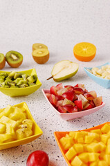 Colorful fruits snacks assortment in small bowls. Raw fresh chopped fruit on a table.