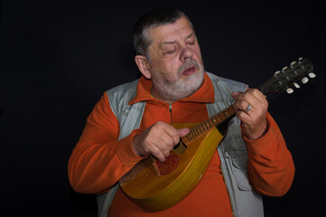 Nice low key portrait of Caucasian senior musician playing  mandolin