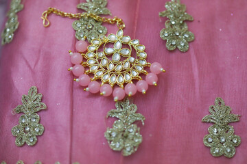 pink kundan stone studded brooch on a pink fabric with a broad designer border
