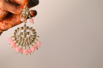 a hand holding kundan style earring