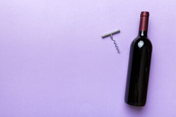 Fototapeta premium One Bottle of red wine with corkscrew on colored table. Flat lay, top view wth copy space
