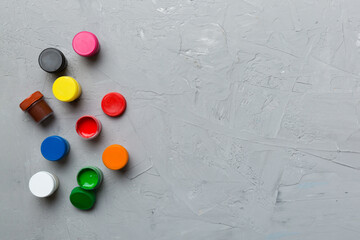 jars with gouache of different colors on Colored background. hobby painting. Top view with empty space. workplace for creativity. home teaching concept drawing
