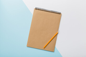 school brown notebook on a colored background, spiral craft notepad on a table Top view