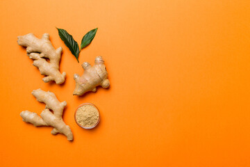Obraz premium Finely dry Ginger powder in bowl with green leaves isolated on colored background. top view flat lay