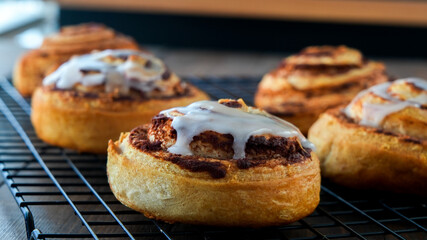 Cinnamon rolls with vanilla icing on cooling rack