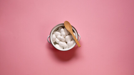 Small white pot filled with white hearts and a wooden spoon on the side. Pink background. Funny...