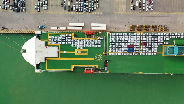 Aerial drone top down pan video of large car carrier ro ro vessel anchored in car terminal of Mediterranean port