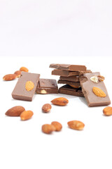 chocolate bars with peanuts, almonds and dried beans on a white background