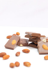 chocolate bars with peanuts, almonds and dried beans on a white background