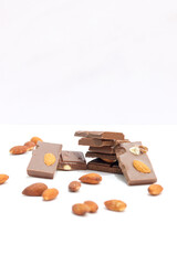 chocolate bars with peanuts, almonds and dried beans on a white background