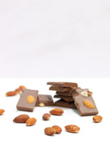 chocolate bars with peanuts, almonds and dried beans on a white background