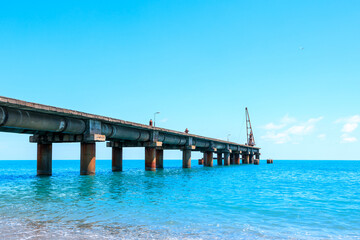 Fototapeta premium pier on the sea coast in daylight, blue sea and blue sky