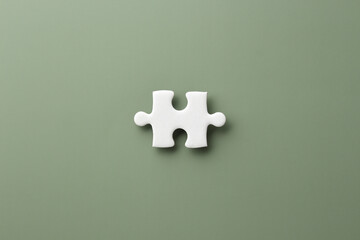white jigsaw puzzle pieces on green paper background with copy space