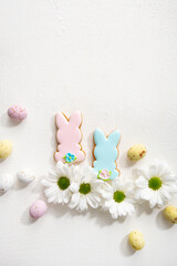 Fototapeta na wymiar Overhead view of two Easter bunny cookies and white flowers on light surface spring holiday