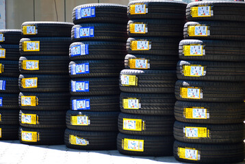 new car tires with price tags and stickers with information stand in rows on the street near the...