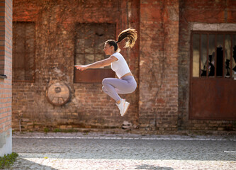 Young woman juping high during training in the urban environment