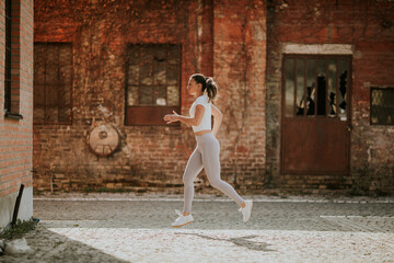 Fototapeta na wymiar Young woman running on the street