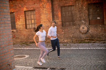 Obraz na płótnie Canvas Young fitness couple running in urban area