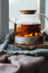 Teapot with flowering tea on the windowsill. 