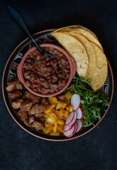 Vegan taco bowl consisting of roasted seitan, bell pepper, salad, refried beans