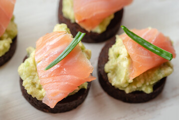Avocado paste with salmon on whole grain pumpernickel bread