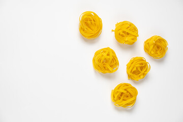 few homemade fettuccine nest in the shape of a triangle isolated on white background