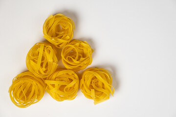 few homemade fettuccine nest in the shape of a triangle isolated on white background