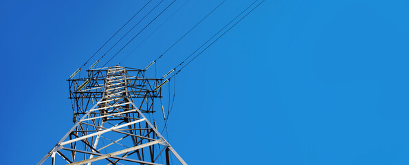 high voltage electric transmission tower over blue sky, panoramic image with space for text