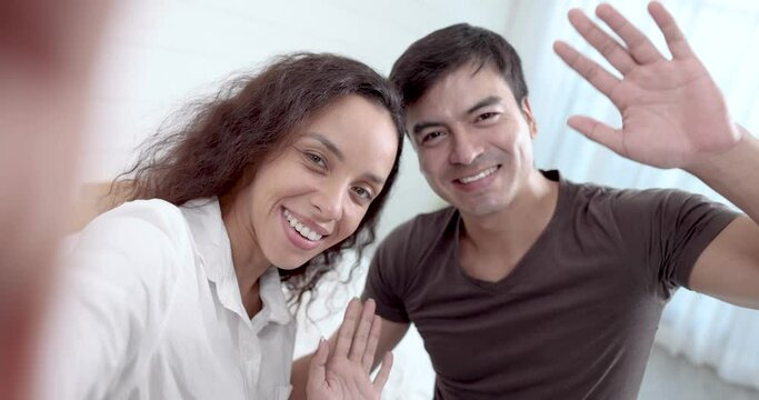 Smiling romantic couple taking selfies with online video calls on smartphones.