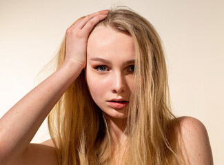 Young woman with blonde hair isolated on beige portrait