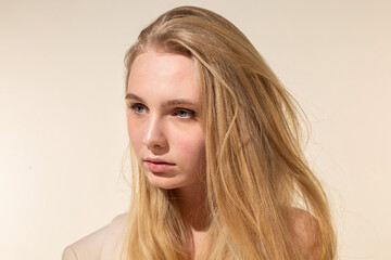 Naklejka premium Young woman with blonde hair isolated on beige portrait with nude make-up