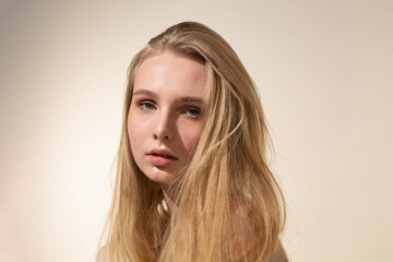 Portrait of young woman with blonde hair isolated on beige with nude make-up