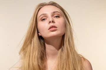Fototapeta premium White young woman with blonde hair isolated on beige with nude make-up