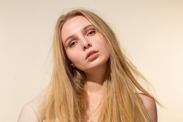 Naklejka premium White young woman with blonde hair isolated on beige portrait