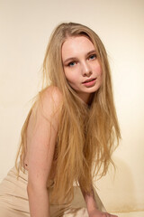 Naklejka premium White young woman with blonde hair isolated on beige sitting