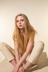 Naklejka premium White european young woman with blonde hair isolated on beige sitting