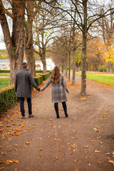 Walking young european married couple in park in autumn