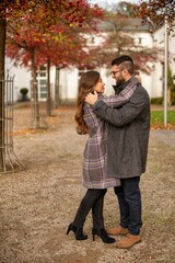 Young european married couple with building behind dancing in autumn park