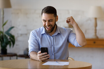 Happy excited smartphone user enjoying win, success, achieve, high job result. Euphoric businessman...