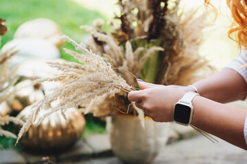 Decorator making holiday decoration. Floristic art autumn decoration. Woman compose dried flowers boho bouquet.