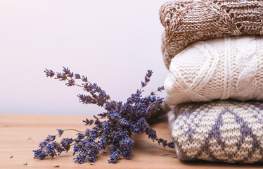 Stack of warm knitted clothes with lavender. Woolen sweaters and dried lavender for protection from moth.