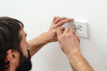 Electrician wiring a new build. Worker installing socket in new house.