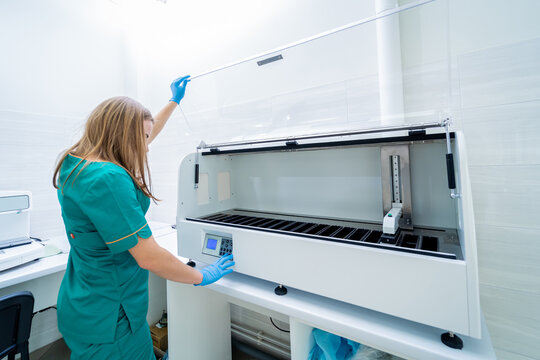 Laboratory assistant works with automatic multi slides stainer at the modern laboratory.