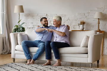 Obraz premium Excited cheerful senior father and adult grownup son giving fist bump, trust and support gesture, having fun together, enjoying funny conversation, friendship, joking, celebrating success, achieve