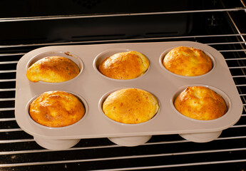 The process of baking muffins at home in the oven. Six muffins on a wire rack in a silicone mold.