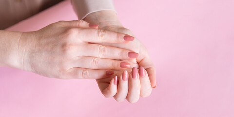 Female hands on a pink background. Beautiful well-groomed hands with classic manicure.
