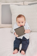 Baby using a ebook sitting on the bed