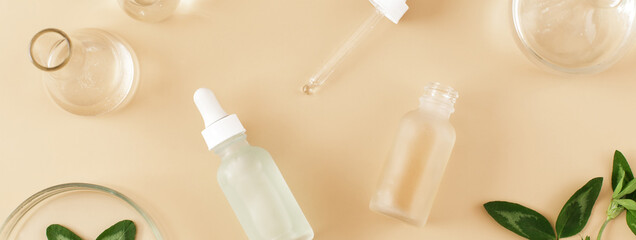 Banner made Laboratory glassware with serum and oil on beige background. Natural medicine, cosmetic research, bio science, organic skin care products. Flat lay, top view.