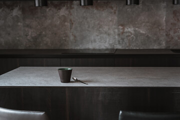 Beautiful coffee cup on island or table countertop in modern home kitchen. Dark grey kitchen design - detail of interior.